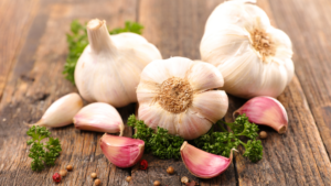 Spicchi di aglio fresco, sottolineando le sue proprietà salutari, inclusi allicina e antiossidanti, che contribuiscono a migliorare la salute del cuore e il sistema immunitario.