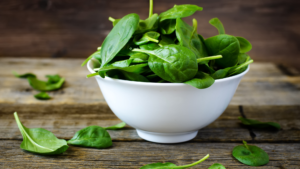 Un mazzetto di spinaci freschi, evidenziando la loro ricchezza in nutrienti essenziali come vitamine A, C, e K, e minerali come ferro e calcio ottimi tra i superfood italiani