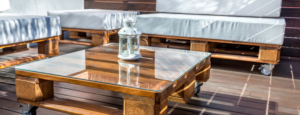 Mobili creativi realizzati con pallet di legno riciclati, inclusi un tavolo e sedie, mostrati in un ambiente domestico, rappresentando un esempio di upcycling